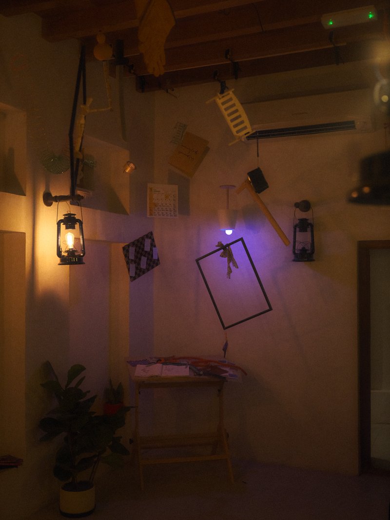 A surreal indoor scene with various objects hanging from the ceiling, including chairs and lanterns.
