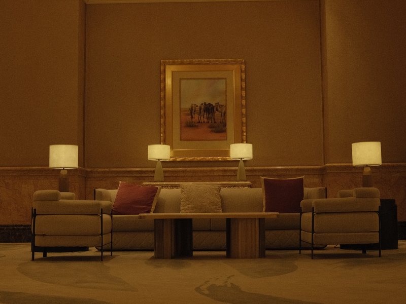 A cozy hotel lobby with a beige sofa, decorative pillows, and lamps illuminating the space.