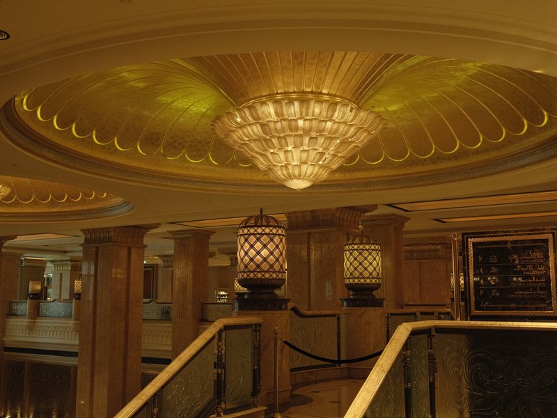Elegant chandelier and ornate ceiling in a luxurious indoor setting.