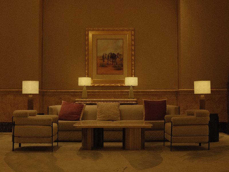 A cozy indoor seating area with a sofa, coffee table, and lamps, illuminated in warm tones.