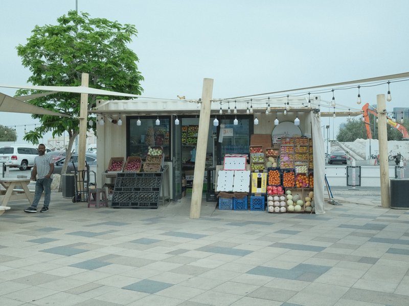 A small market stall with colorful fruit displays under a cloudy sky.