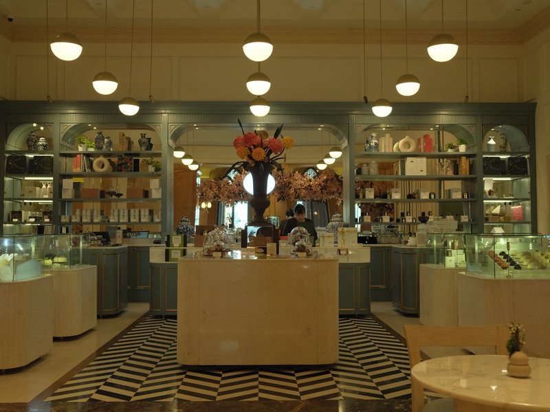 Interior of a stylish shop with display cases, shelves, and a floral centerpiece.