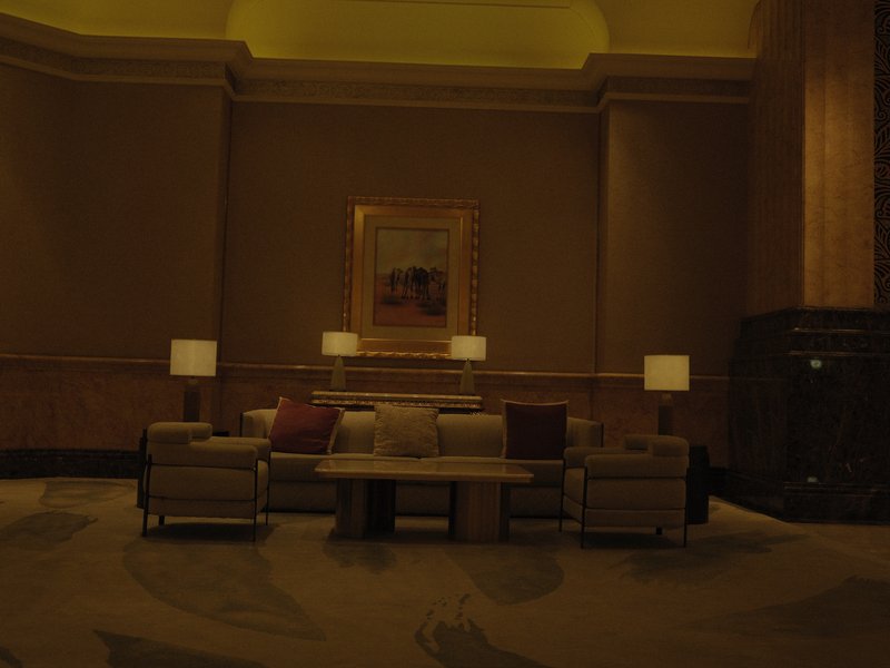 A cozy indoor lounge area with soft lighting, featuring a sofa, coffee table, and lamps.
