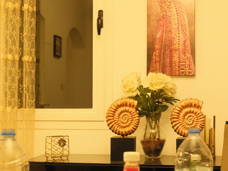 A cozy indoor scene featuring a vase of white flowers, decorative shells, and a framed artwork on the wall.