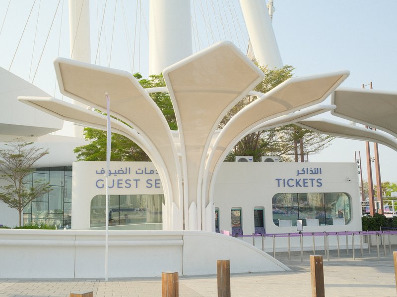 Modern architectural ticket booth with a flower-like design in a sunny outdoor setting.