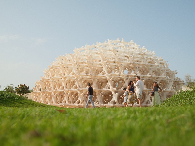 A group of people interacting around a large, dome-shaped structure made of interconnected hexagonal shapes.