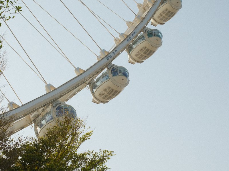 Close-up view of a ferris wheel with several cabins against a clear blue sky.