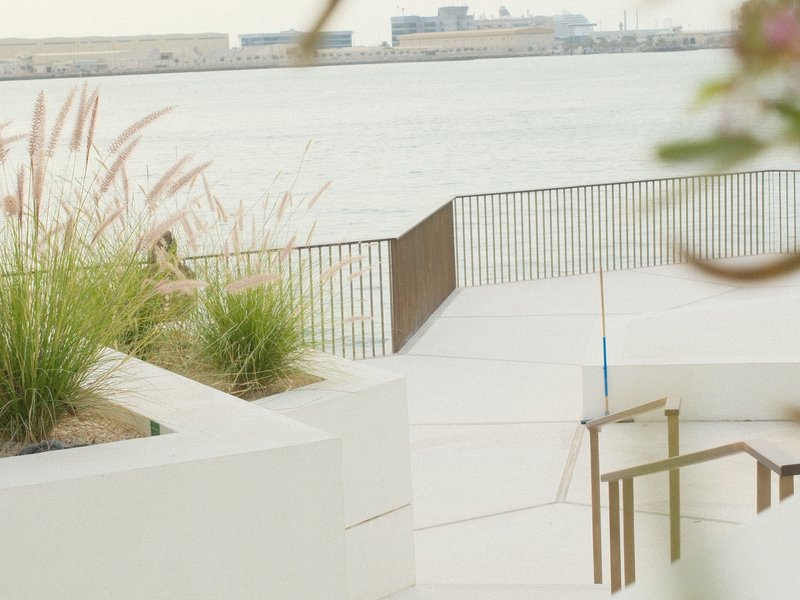 A serene waterfront scene with grasses and a modern walkway leading to the water's edge.