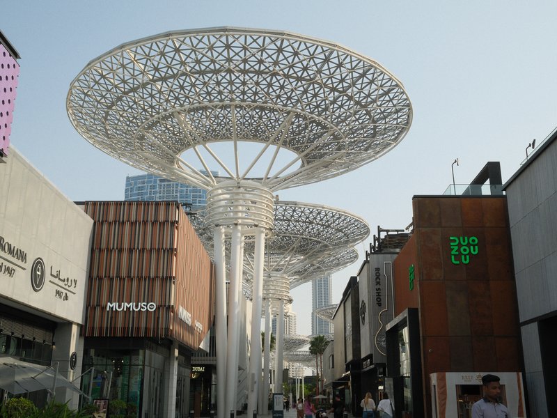 Modern architectural structures with large, circular canopies above a shopping street.