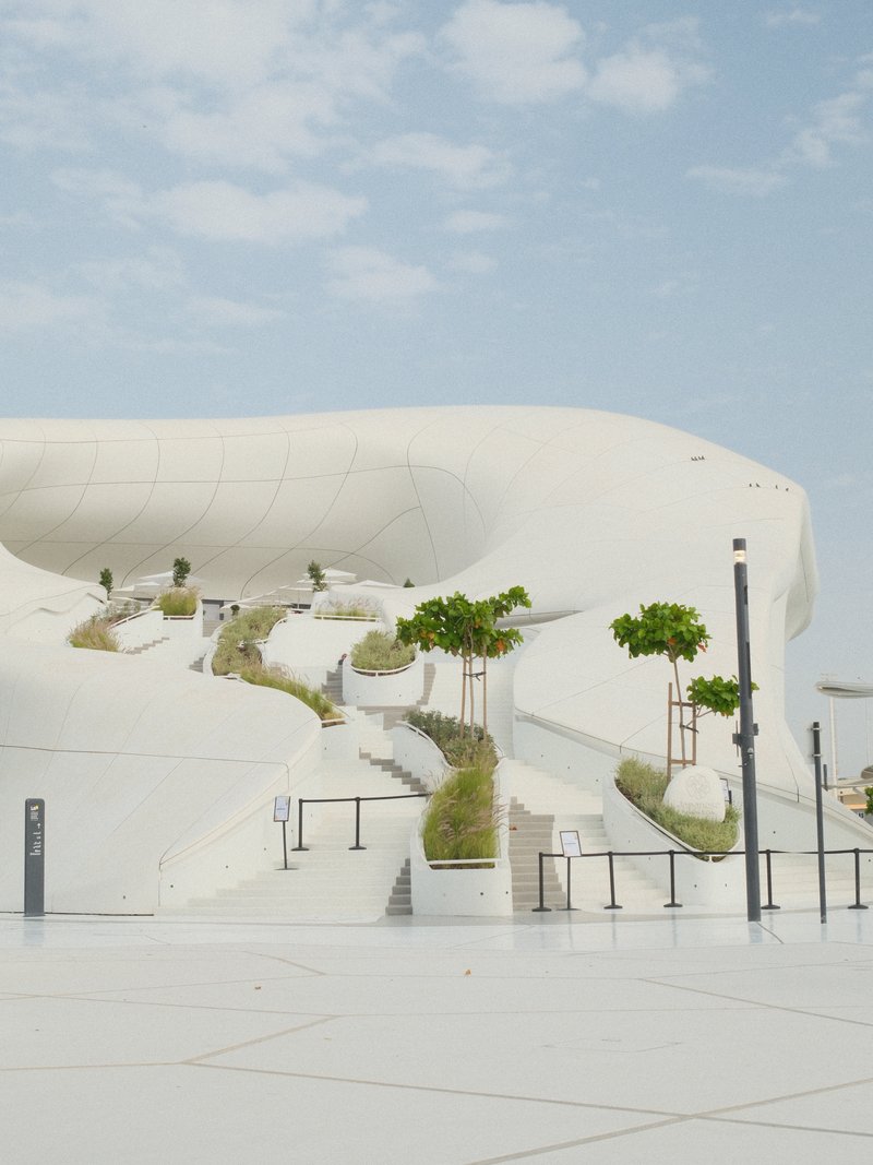 A modern architectural structure with smooth white surfaces and greenery integrated into the design.