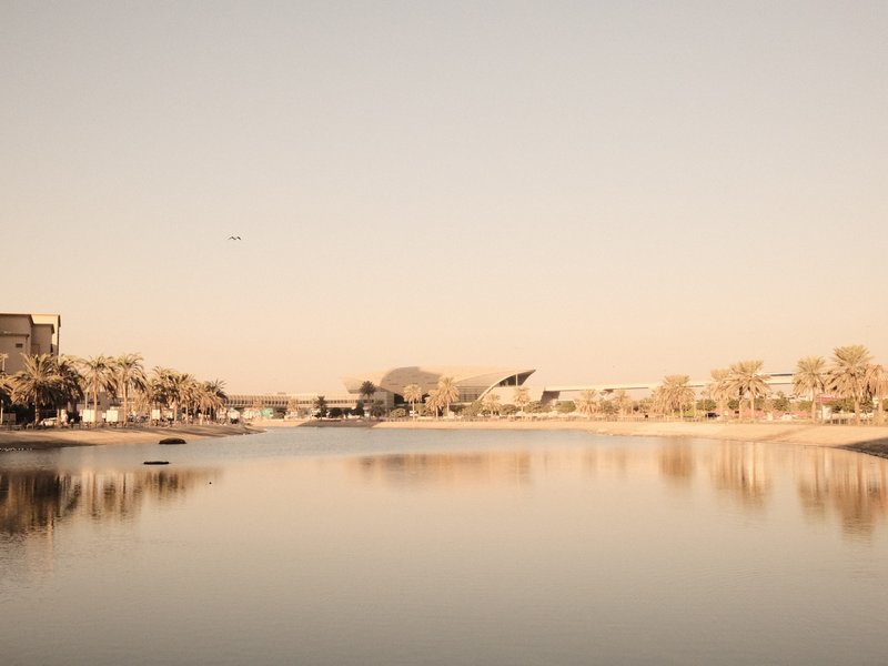 A serene river scene with soft pastel colors reflecting the landscape and buildings along the shore.
