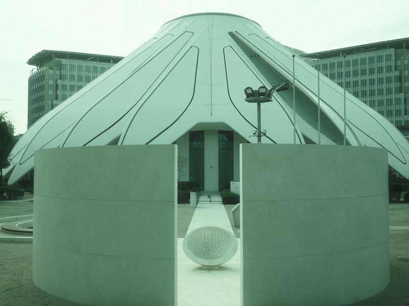 A modern architectural structure resembling a large flower with a circular base and white exterior.