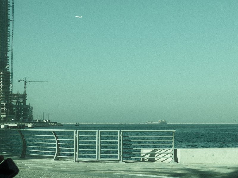 A serene coastal scene featuring a distant ship on the horizon with a clear blue sky.