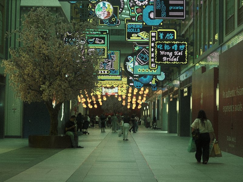 A vibrant indoor walkway adorned with colorful neon signs and a decorative tree.