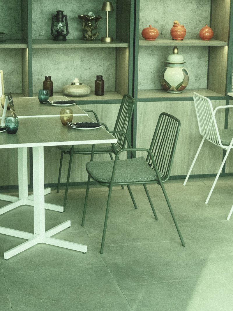 A modern dining area with minimalist furniture, featuring green and white chairs and decorative shelves.