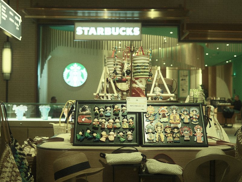 A Starbucks store interior featuring a display of colorful merchandise and a large logo in the background.
