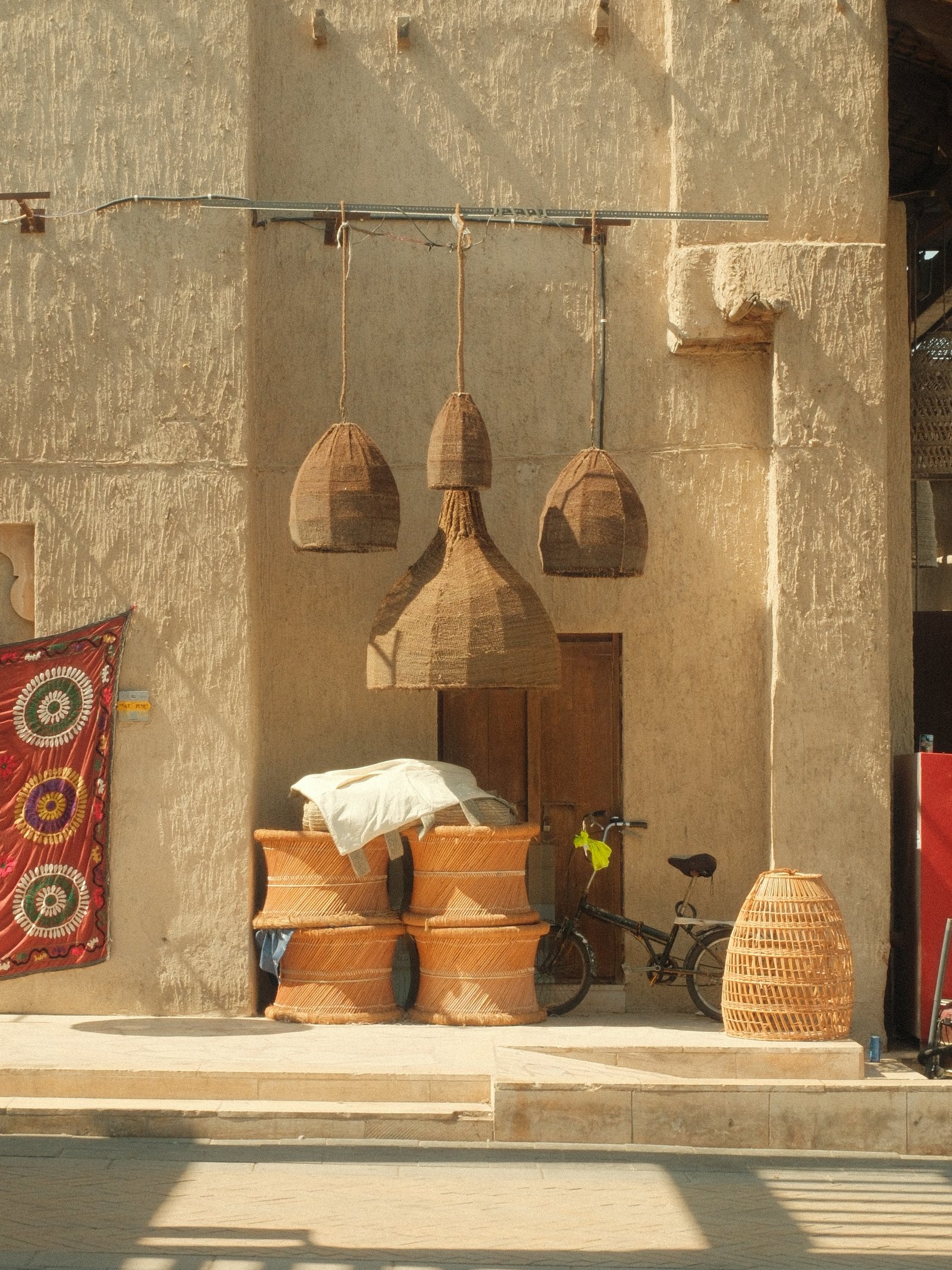 A rustic scene featuring woven baskets and hanging light fixtures against a textured wall.