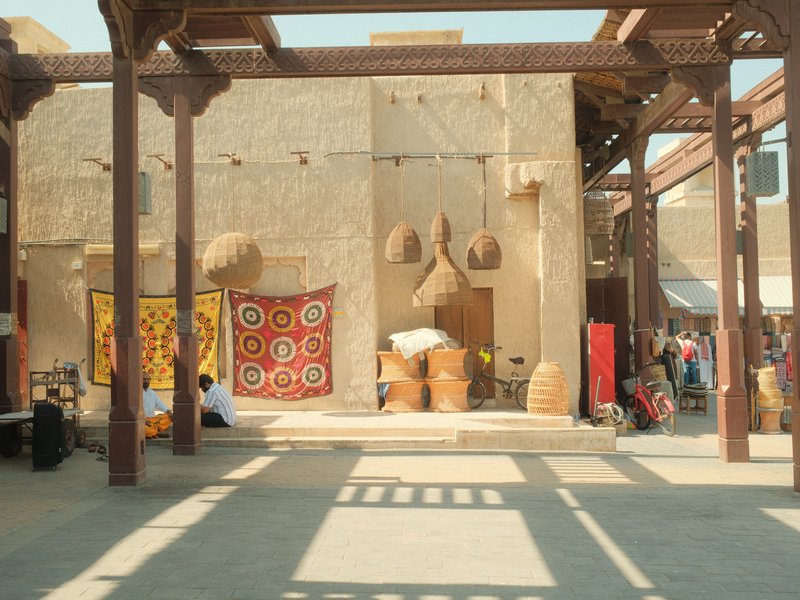 A traditional market scene with woven baskets and colorful textiles in a sunlit outdoor setting.