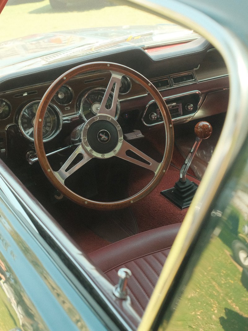 Interior view of a classic car showing the steering wheel, dashboard, and gear shift.