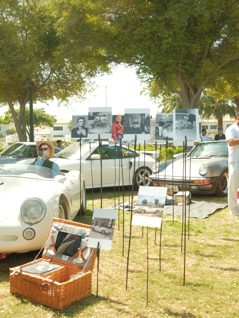 Classic cars displayed outdoors with photographs and people enjoying the event.