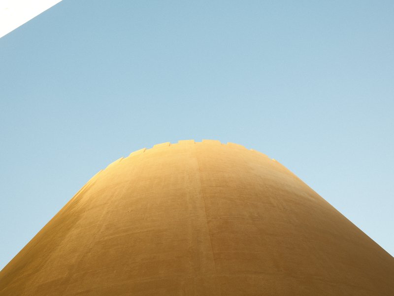 Close-up of a large yellow structure against a clear blue sky.