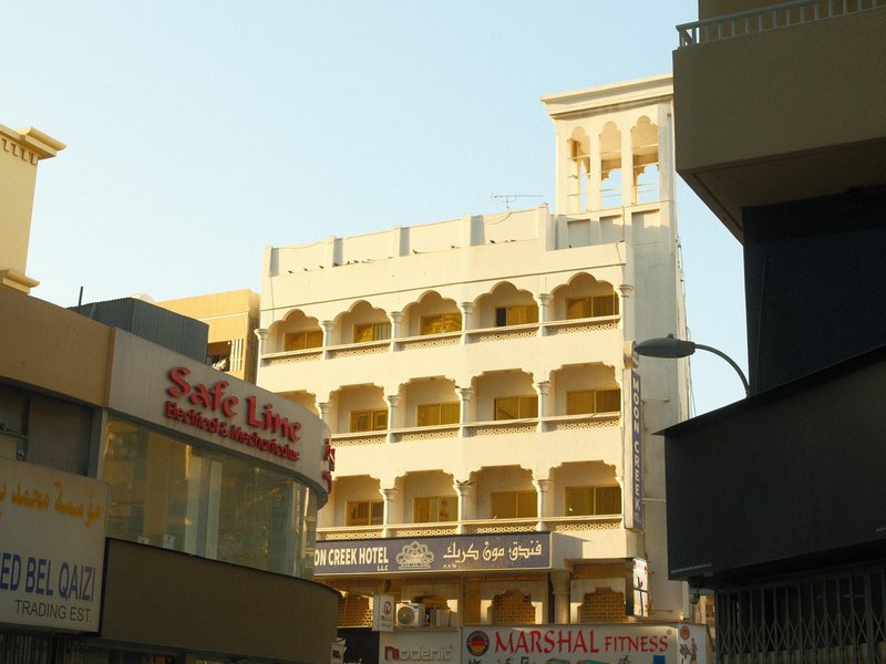 A multi-story building with arched windows and a tower, surrounded by urban structures.