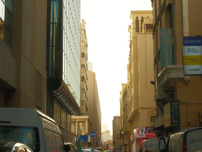 Narrow urban street with buildings on either side, sunlight illuminating the scene.