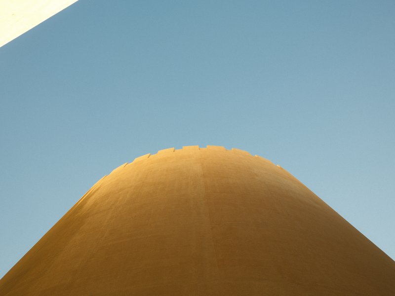A close-up view of a curved architectural structure against a clear blue sky.