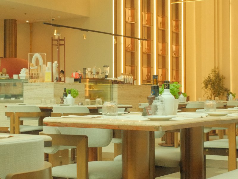 A modern restaurant interior with wooden tables, elegant decor, and soft lighting.