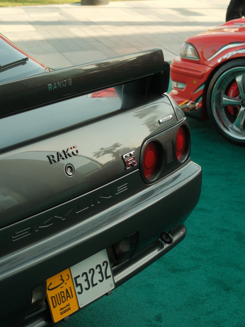 Close-up of a grey Nissan Skyline sports car with a prominent rear wing and Dubai license plate.