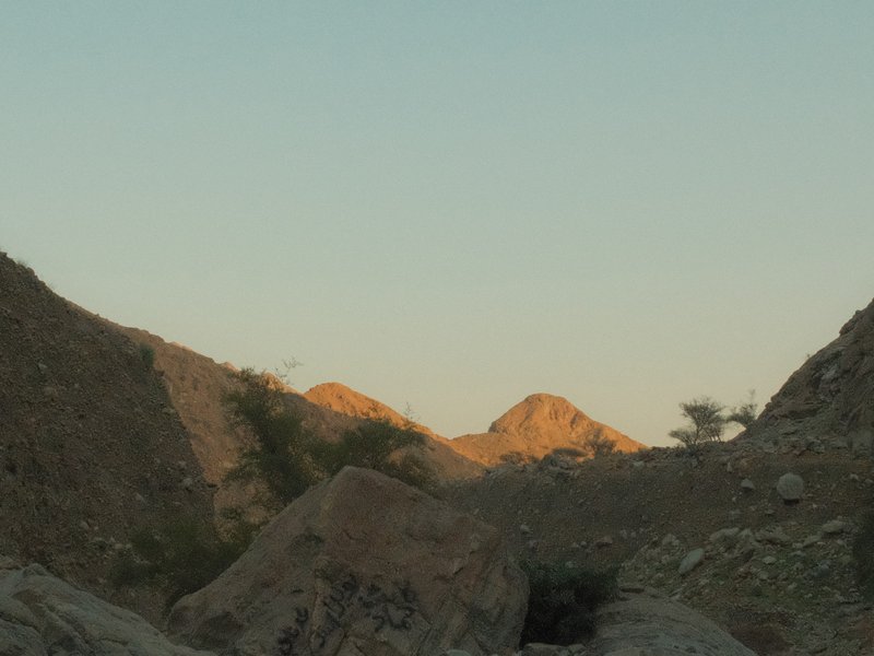 A rocky landscape with distant mountains illuminated by soft evening light.