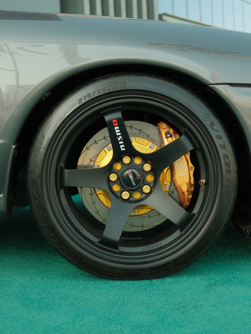 Close-up of a black car wheel with gold brake calipers and a textured surface.