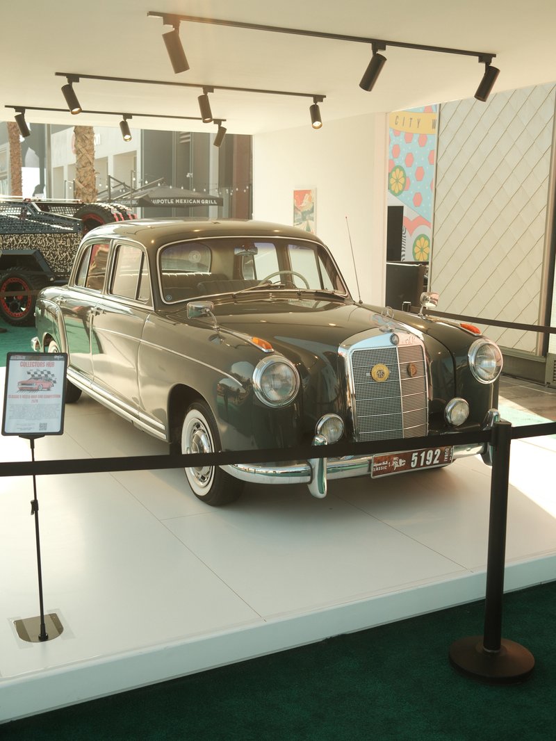 A vintage Mercedes-Benz car displayed in a modern exhibition space with bright lighting.