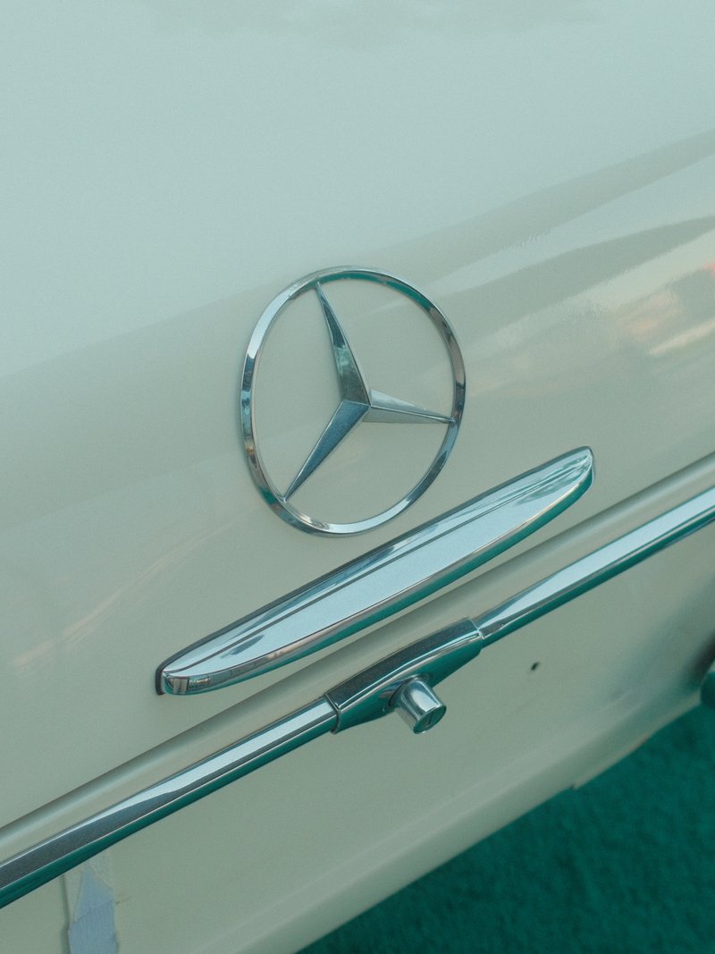 Close-up of a vintage Mercedes-Benz logo on a cream-colored car.