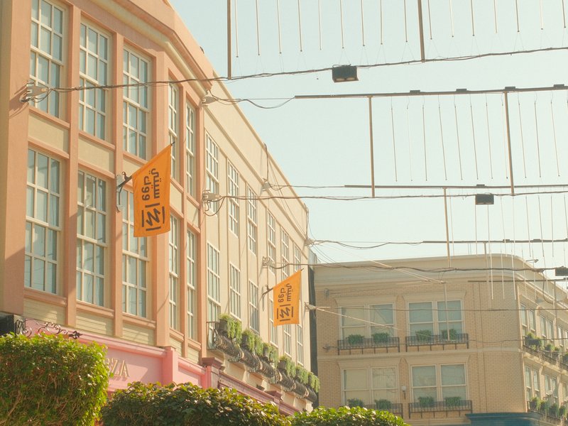 A pastel-colored building with decorative flags and plants, under a clear sky.
