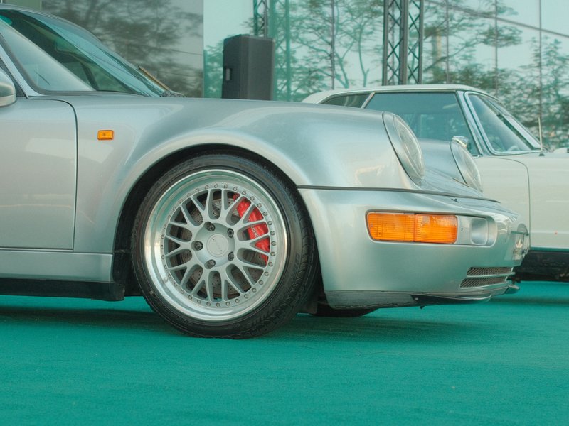 Close-up of a silver sports car with detailed alloy wheels parked on a green surface.