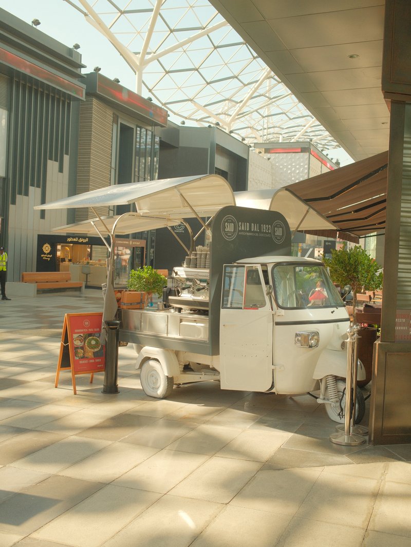 A vintage food cart in a modern indoor shopping mall with a bright, airy atmosphere.