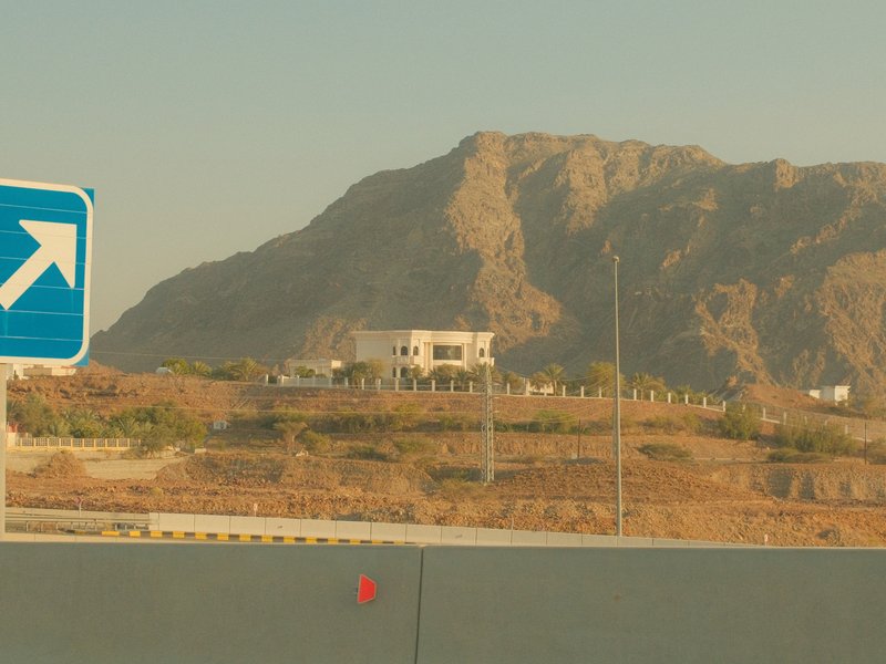 A distant view of a mountain with a building on a hillside, captured during golden hour.
