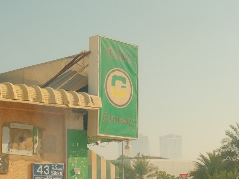 A green sign with a logo and text, partially obscured by haze, in an urban setting.