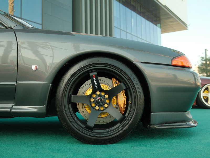 Close-up of a sleek gray sports car showcasing a black alloy wheel with yellow brake calipers.