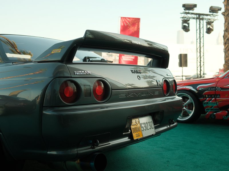 Rear view of a gray sports car with a prominent spoiler, parked at an automotive event.