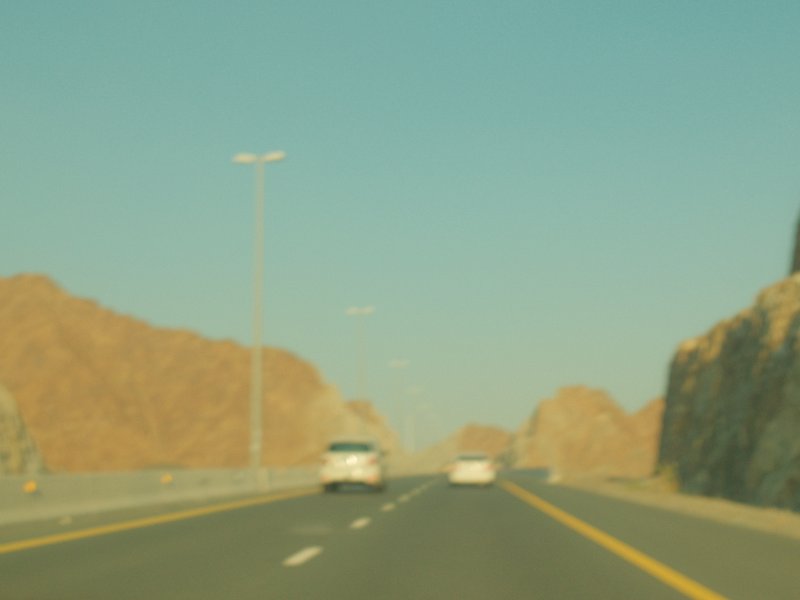 A highway surrounded by rocky mountains under a clear blue sky.