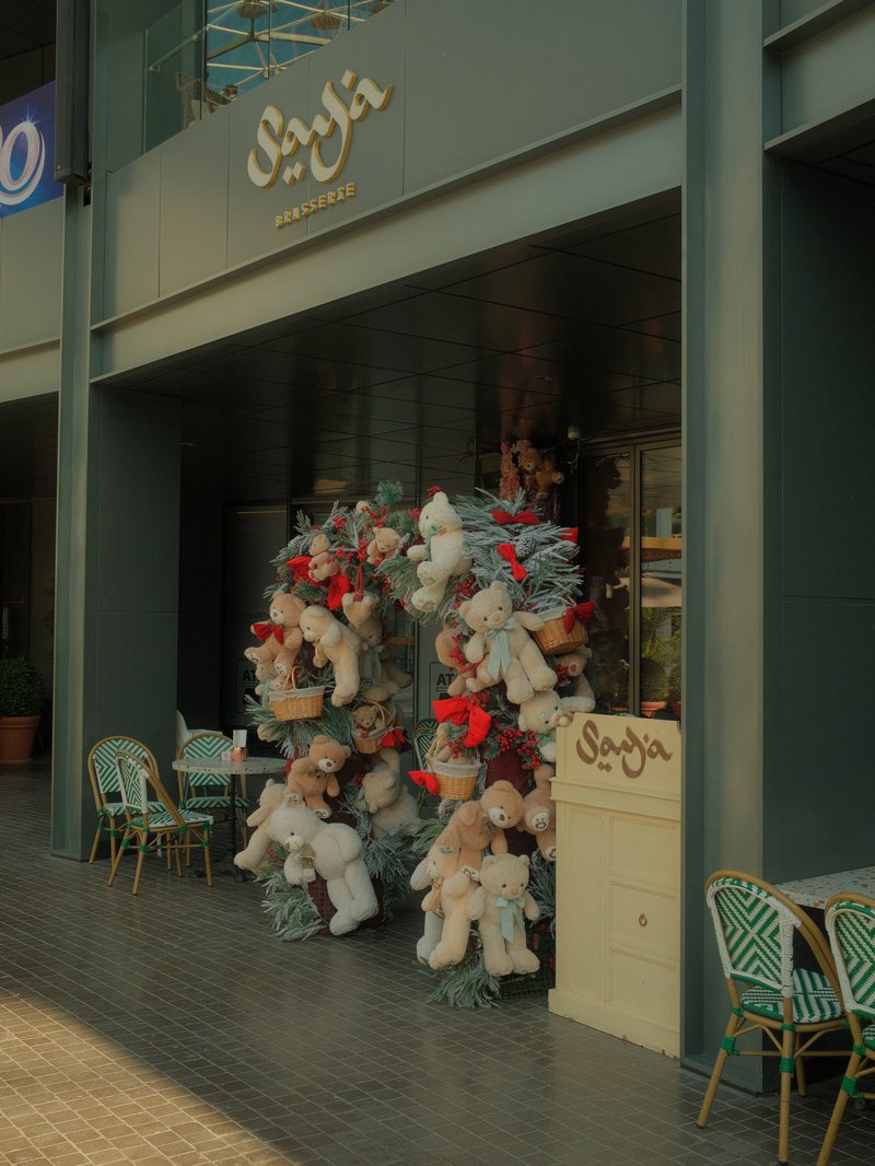 A storefront adorned with floral decorations and plush toys, featuring outdoor seating.