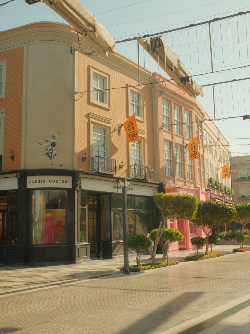 Colorful buildings with shops and decorative trees under a clear sky.