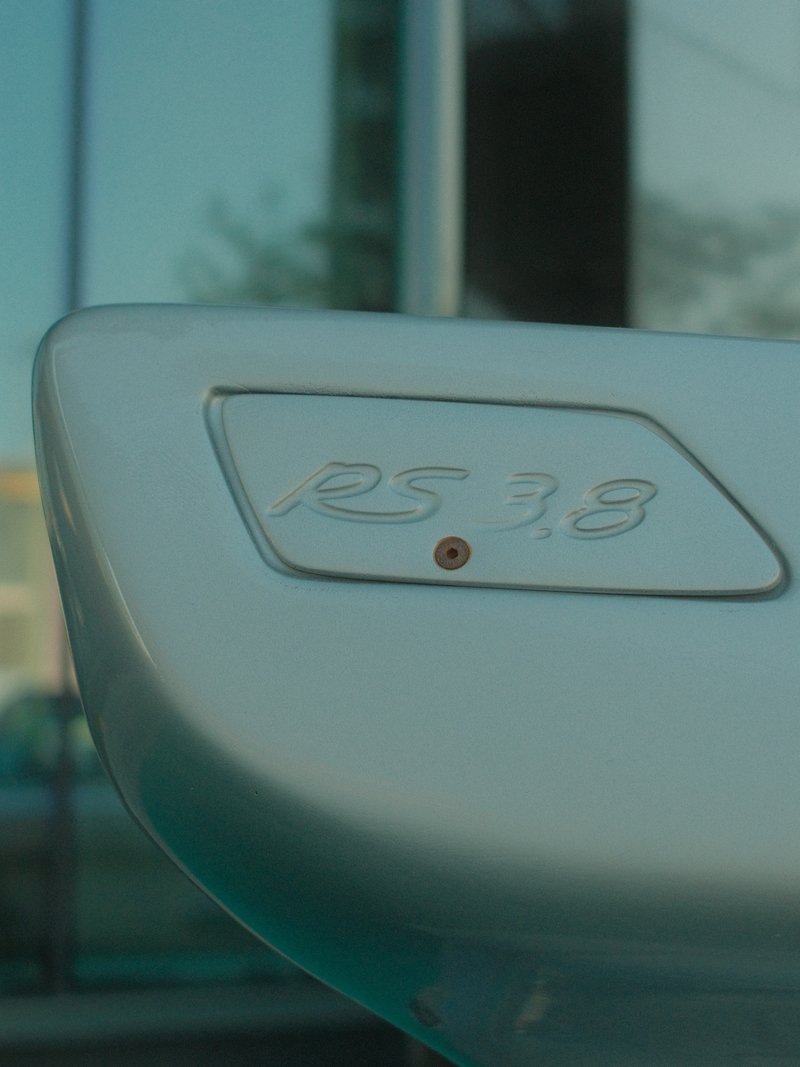 Close-up of a car's rear spoiler with the model number 'RS 3.8' engraved on it.