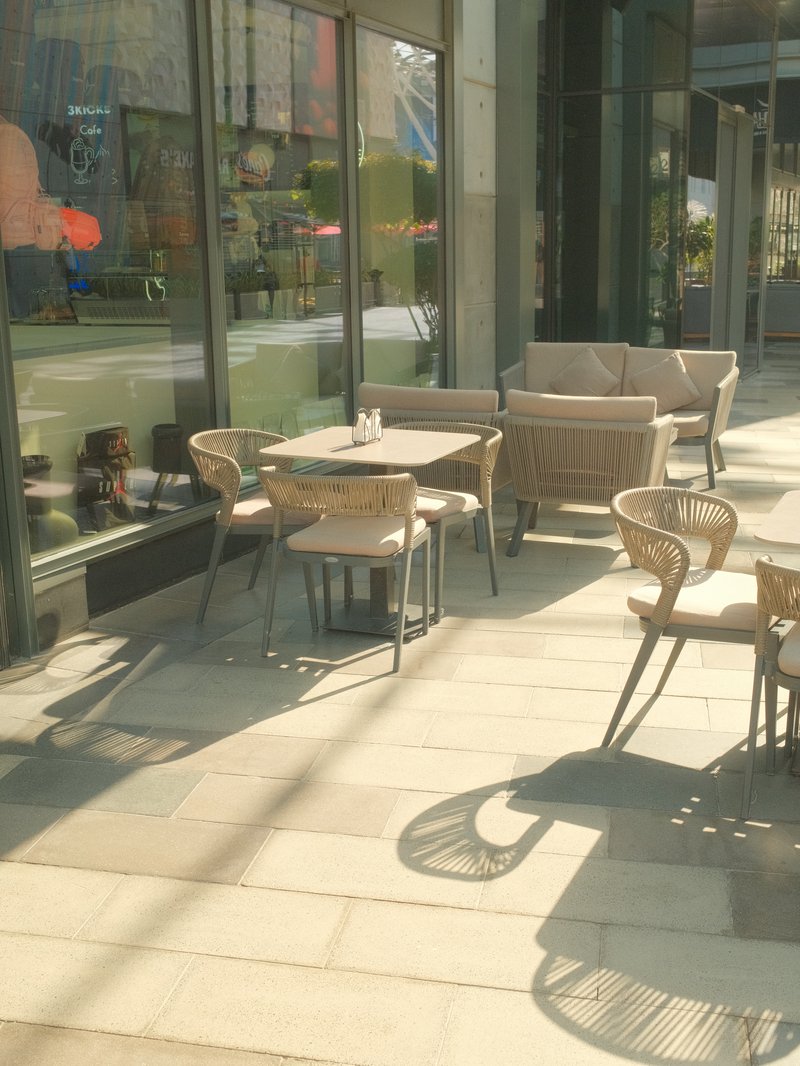 Outdoor café seating area with tables and chairs on a sunny day.