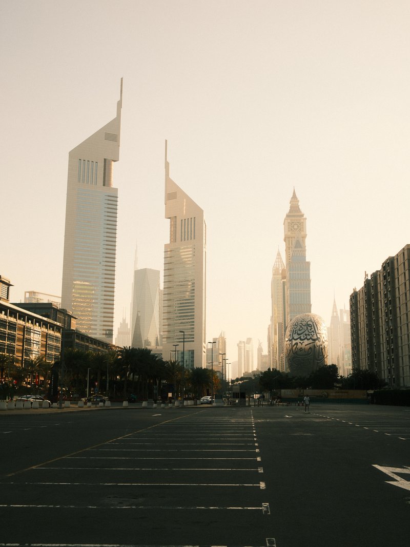 A view of tall skyscrapers in a city during golden hour, with an empty street in the foreground.