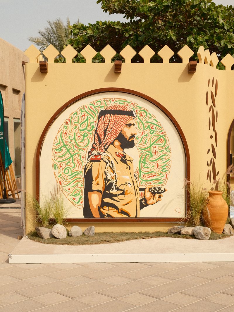 A mural of a man in traditional attire, surrounded by decorative elements and greenery.
