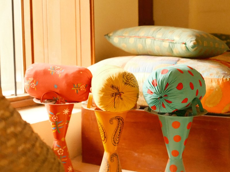 Colorful cushions on wooden stools in a cozy indoor setting.