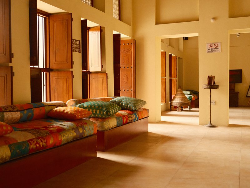 Interior of a cozy room with colorful cushions on a wooden bench and open windows.